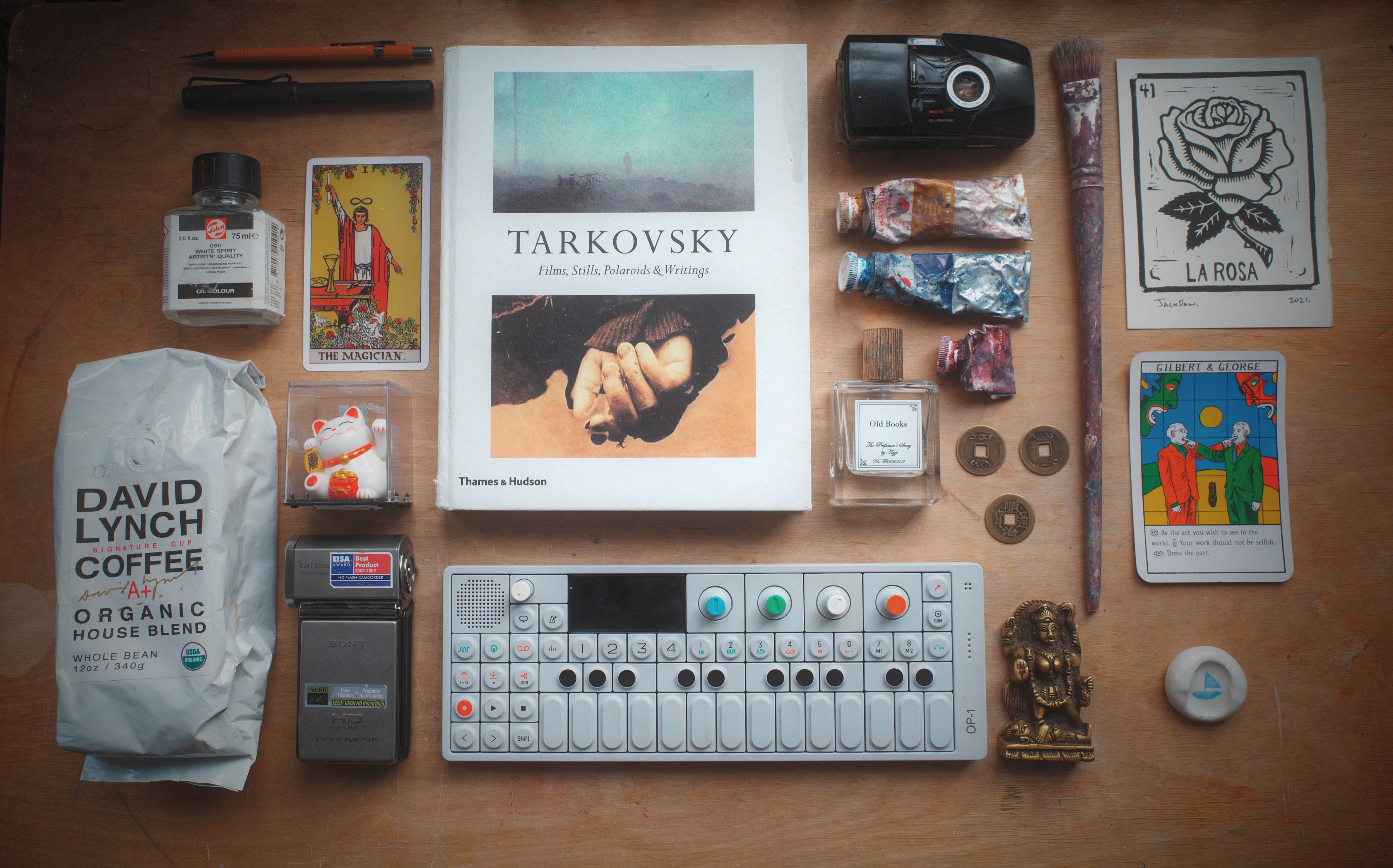 Studio table with a Tarkovsky book, camcorder, OP1, paint, brush, cards and personal objects